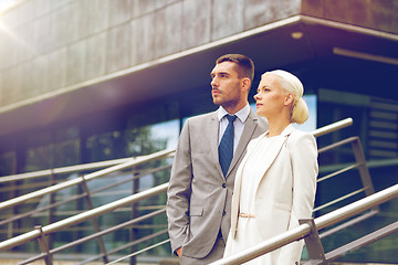 Image showing serious businessmen standing over office building