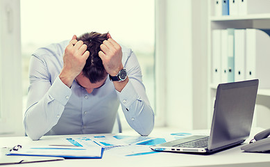 Image showing stressed businessman with papers in office