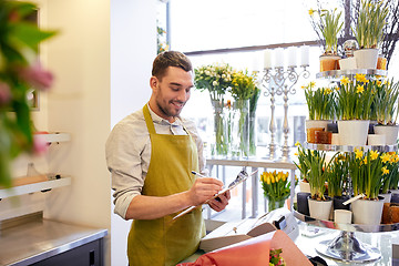 Image showing florist man with clipboard at flower shop counter