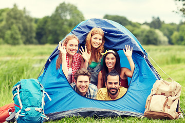 Image showing happy friends with backpacks in tent at camping