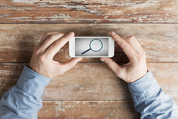 Image showing close up of hands with magnifier on smartphone