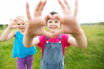 Image showing happy kids showing heart shape sign outdoors