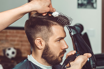 Image showing The hands of young barber making haircut to attractive man in barbershop