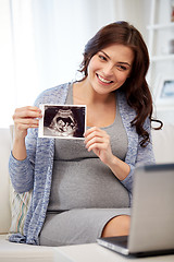 Image showing happy pregnant woman with ultrasound image at home