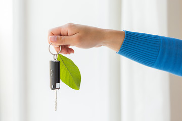 Image showing close up of hand holding car key with green leaf