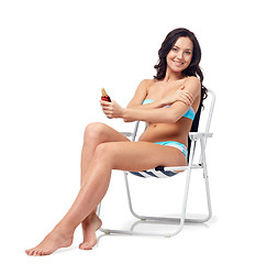 Image showing happy woman sunbathing and applying sunscreen