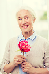 Image showing happy smiling senior woman with flower at home