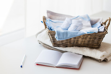 Image showing close up of baby clothes for newborn and notebook