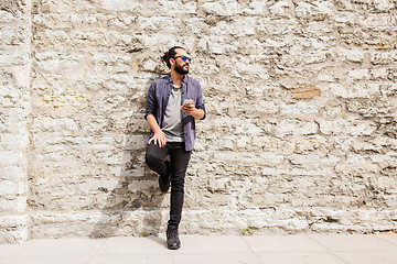 Image showing man with smartphone at stone wall on city street