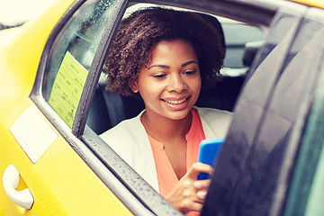 Image showing happy african woman texing on smartphone in taxi