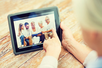 Image showing senior woman with family photo on tablet pc screen