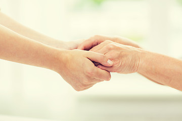 Image showing close up of senior and young woman holding hands