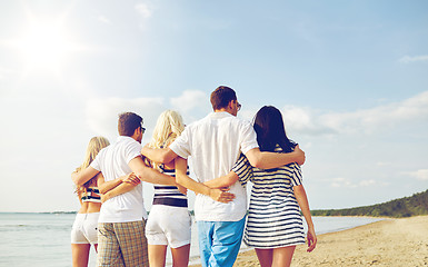 Image showing smiling friends hugging and walking on beach