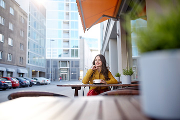 Image showing happy woman drinking cocoa at city street cafe