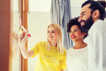 Image showing happy creative team writing on stickers at office