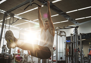Image showing man flexing abdominal muscles on pull-up bar