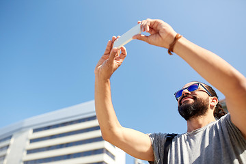 Image showing man taking video or selfie by smartphone in city