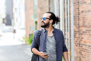 Image showing man with earphones and smartphone walking in city