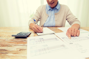 Image showing senior woman with papers and calculator at home