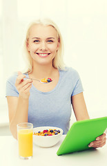 Image showing smiling woman with tablet pc eating breakfast 