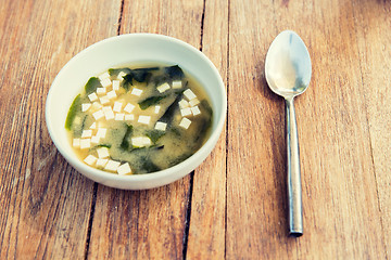 Image showing bowl of soup with tofu cheese and spoon on table