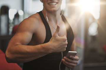 Image showing happy man with smartphone and earphones in gym