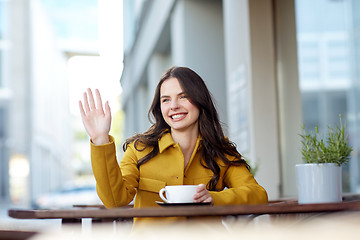 Image showing happy woman drinking cocoa at city street cafe