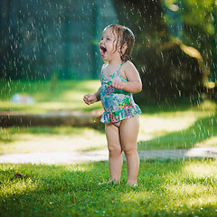 Image showing The little baby girl playing with garden sprinkler.