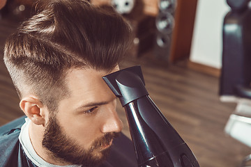 Image showing The hands of young barber making haircut to attractive man in barbershop