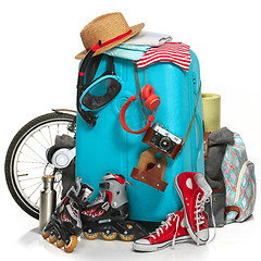 Image showing The blue suitcase, sneakers, clothing, hat, and retro camera on white background.