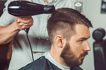 Image showing The hands of young barber making haircut to attractive man in barbershop