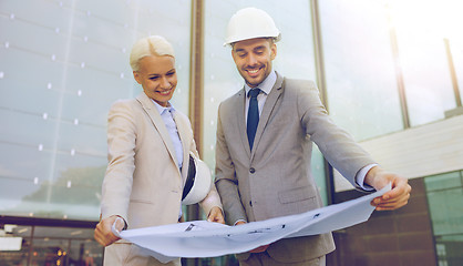 Image showing smiling businessmen with blueprint and helmets