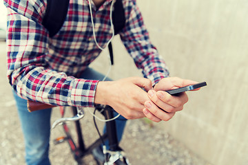 Image showing hipster man in earphones with smartphone and bike