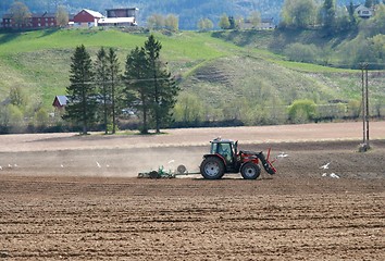 Image showing Farmer harrowing field