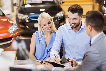 Image showing happy couple with car dealer in auto show or salon