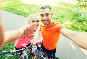 Image showing couple with bicycle taking selfie outdoors