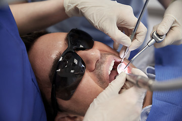 Image showing dentist hands treating male patient teeth