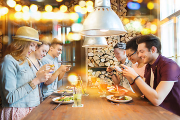 Image showing happy friends with smartphones picturing food