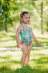 Image showing The little baby girl playing with garden sprinkler.