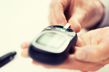 Image showing senior woman with glucometer checking blood sugar