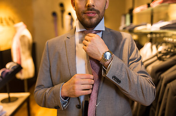 Image showing close up of man tying tie at clothing store