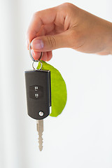 Image showing close up of hand holding car key with green leaf