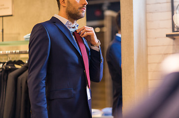 Image showing close up of man trying tie on at clothing store