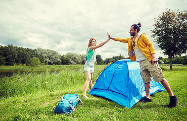 Image showing happy couple setting up tent outdoors