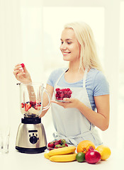 Image showing smiling woman with blender preparing shake at home