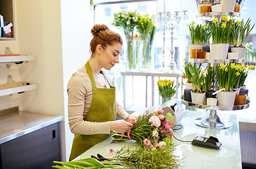 Image showing smiling florist woman making bunch at flower shop