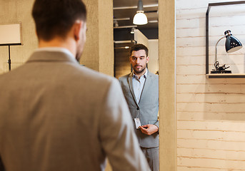 Image showing man trying suit on at mirror in clothing store