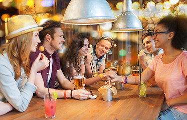 Image showing happy friends with drinks talking at bar or pub