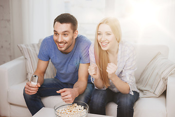 Image showing smiling couple with popcorn cheering sports team