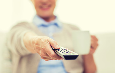 Image showing senior woman watching tv and drinking tea at home